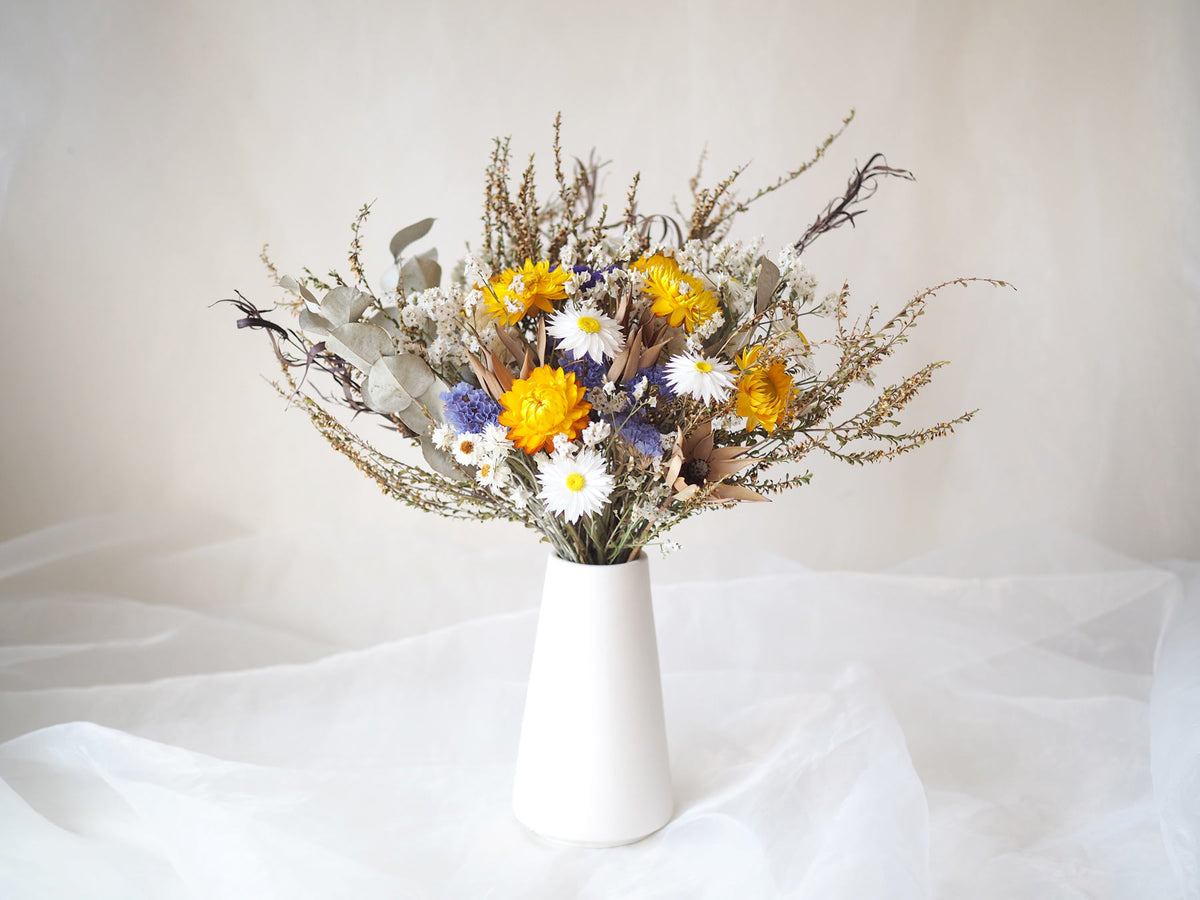 Bouquet of yellow white native Australian dried flowers in a white vase 
